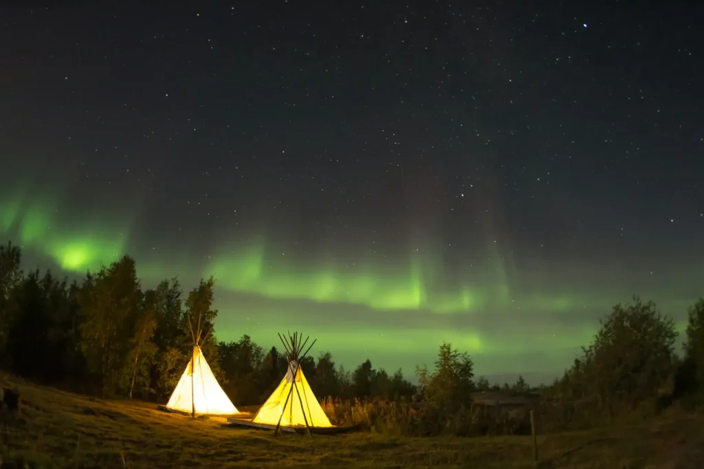 Aurora borealis over traditional tipi at Aurora Village near Yellowknife Canada
